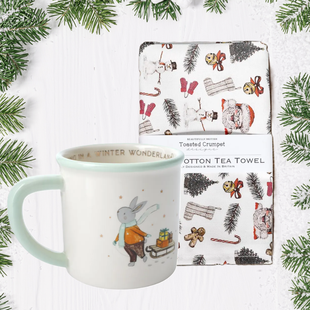 Mug and tea towel with Christmas design on a white background with greenery
