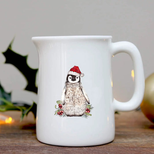 White mug with a penguin wearing a Santa hat design on a wooden surface.