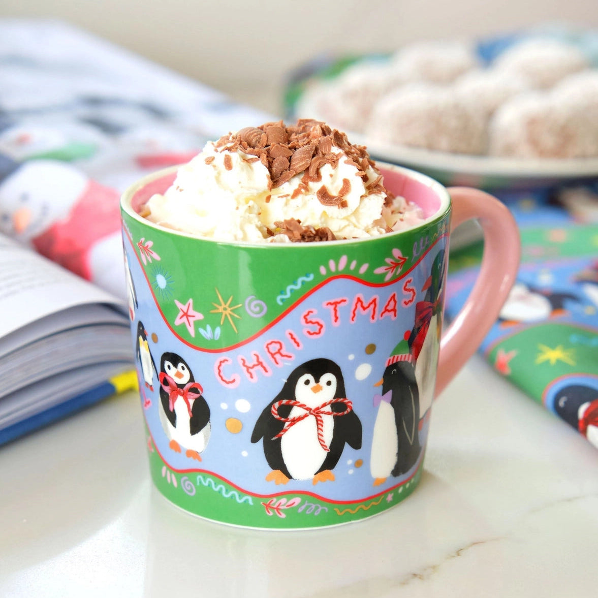 Christmas-themed mug with penguins and hot chocolate in a cozy setting