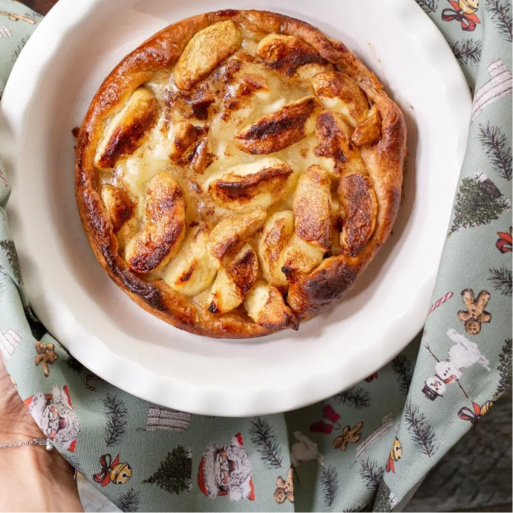 Baked dish in a white dish held by a person on a patterned napkin
