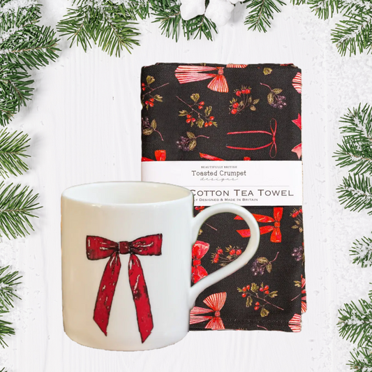 Mug and tea towel with with red bow festive design pattern on a white background
