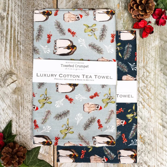 Christmas theme tea towels with penguin design on a wooden surface
