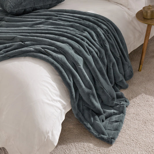 Charcoal throw draped over a bed in a bedroom setting