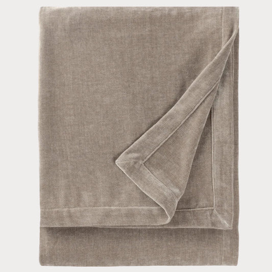 Folded beige throw blanket on a white background