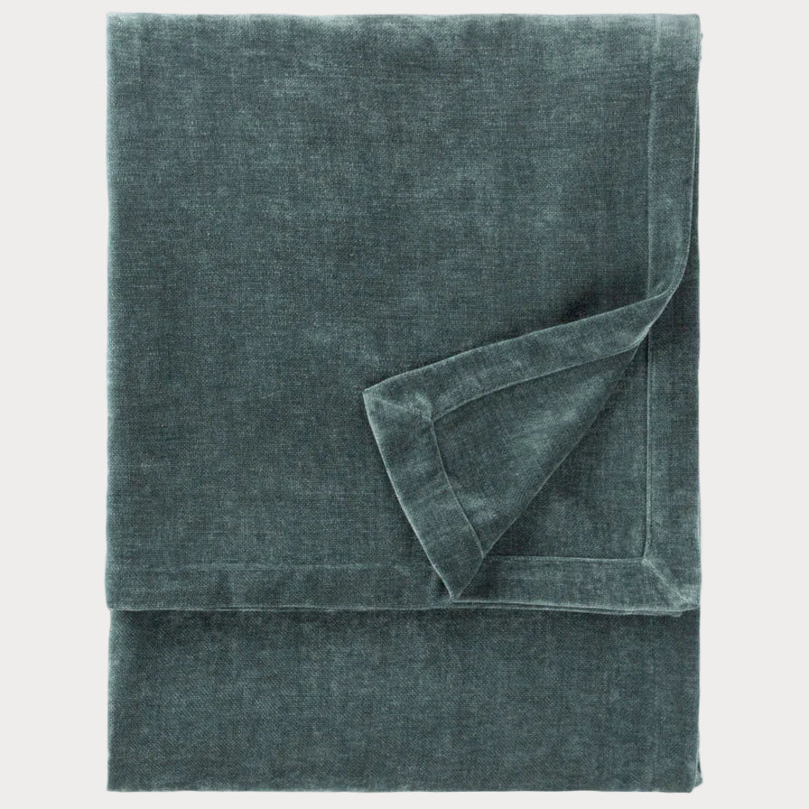 Folded teal throw on a white background