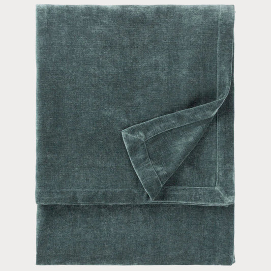 Folded teal throw on a white background