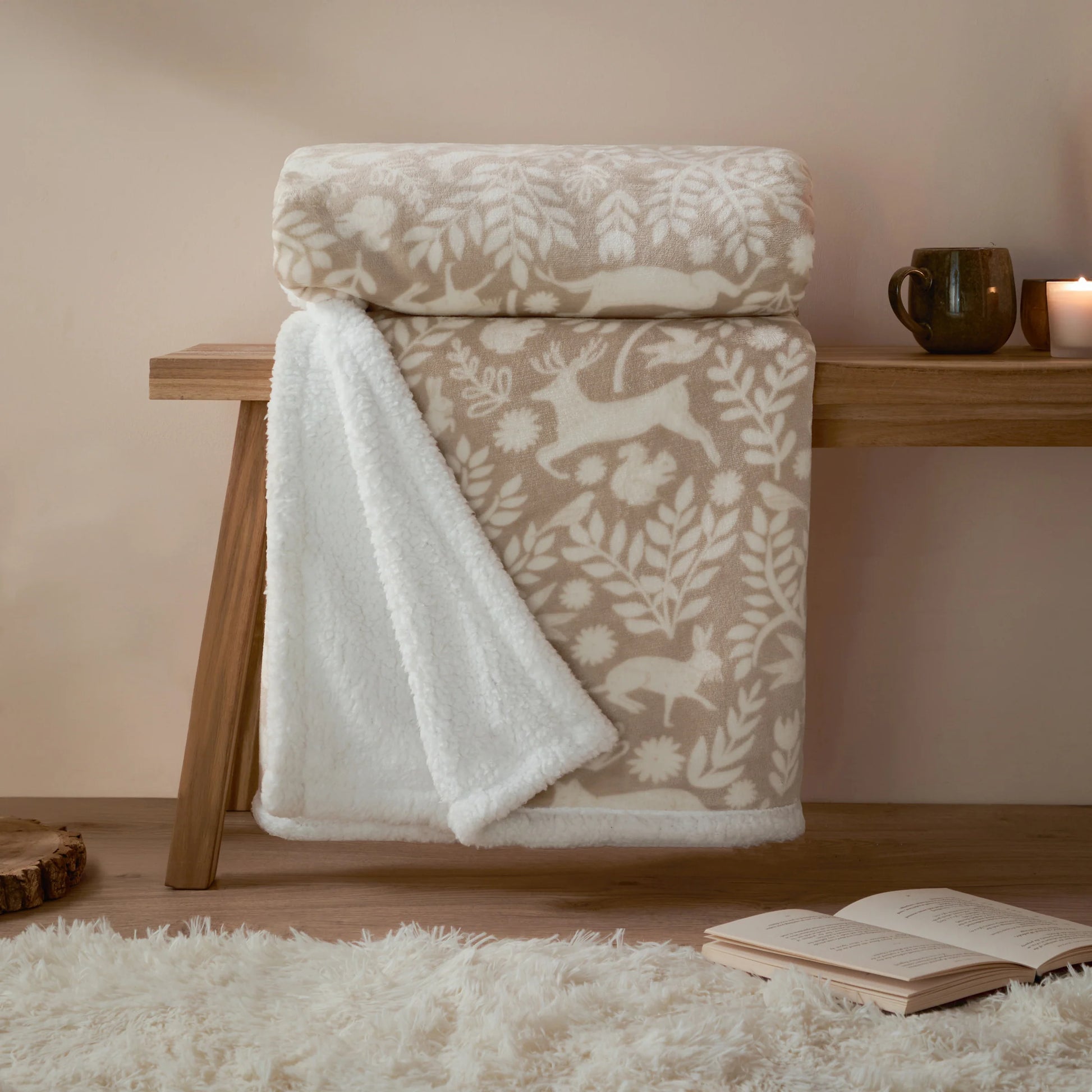 Patterned throw draped over a wooden bench with a cup and candle in the background.