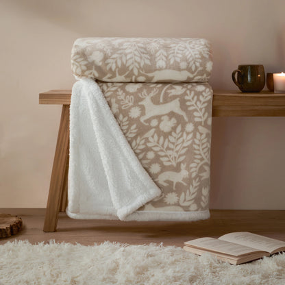 Patterned throw draped over a wooden bench with a cup and candle in the background.