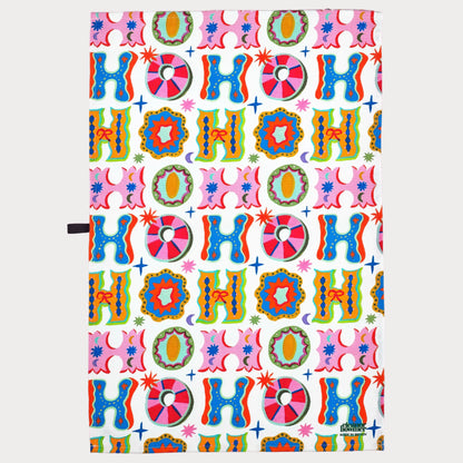 Colorful 'HO HO HO' patterned paper on a pink background